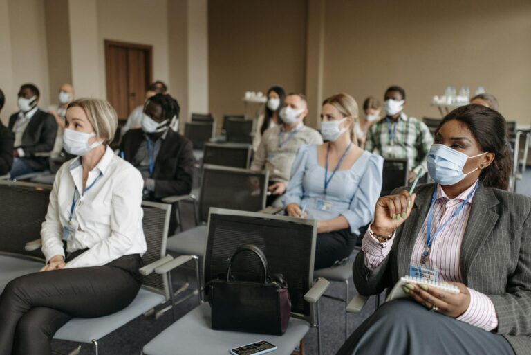 Diverse group of professionals in a conference room wearing face masks during a business seminar.