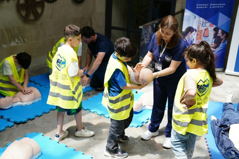 Kids learning CPR skills in an educational safety workshop indoors led by instructor.
