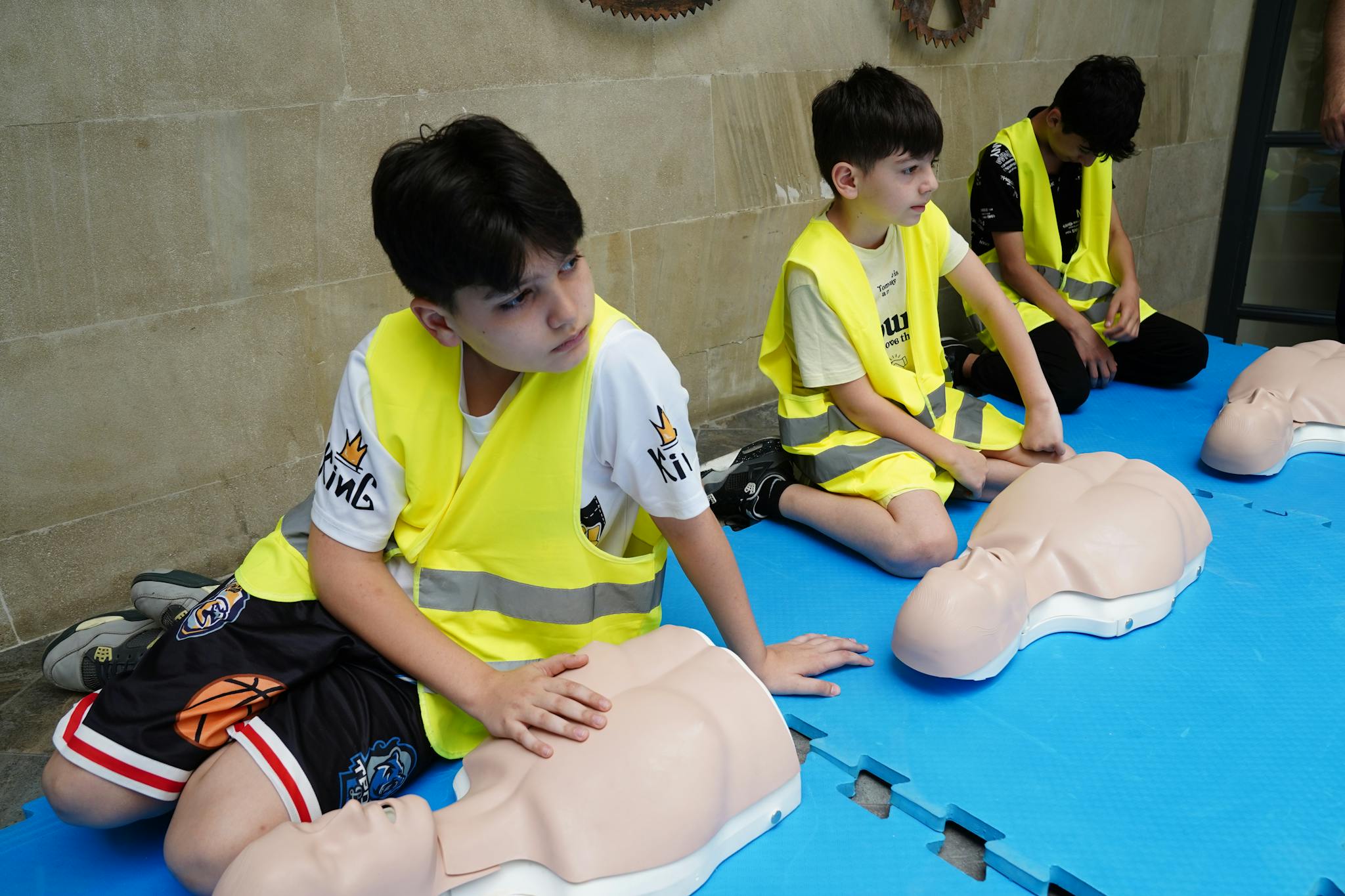 Young children learning CPR techniques using mannequins at a training session.